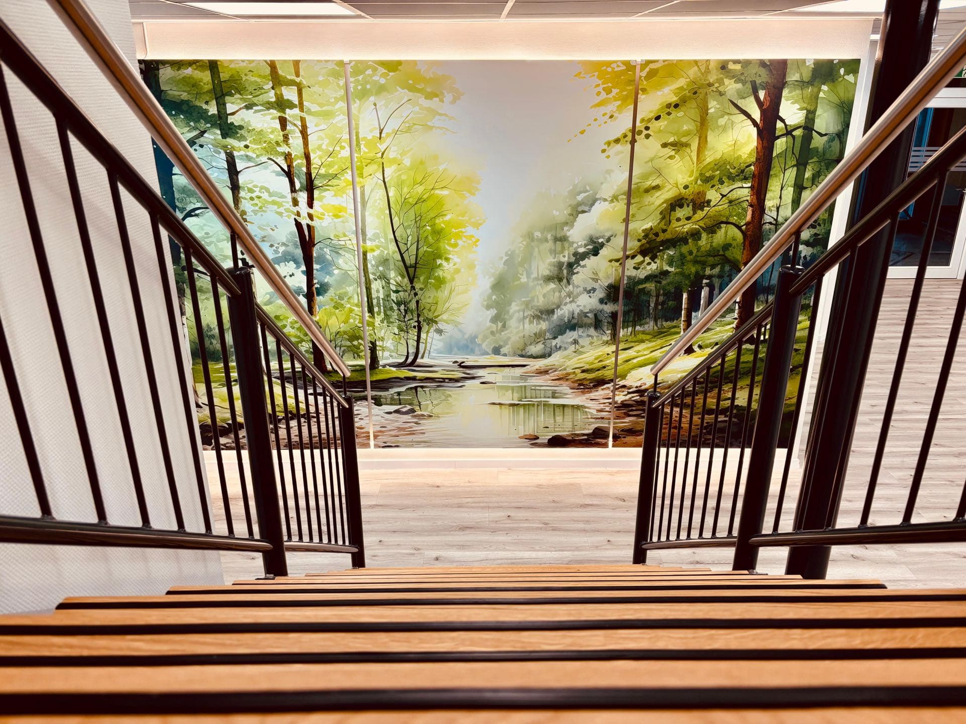 Einladendes Treppenhaus mit großem Wald- und Flussmotiv Wandbild im Gesundheitshaus Garrel